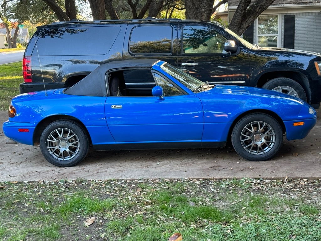 1991 Mazda Miata NA · Mariner Blue side profile in the driveway · soft top up · original lines